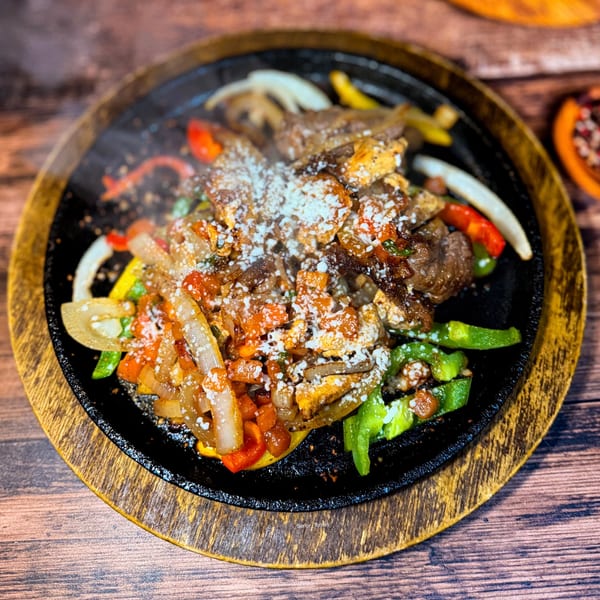 Sizzling Señor Tomas fajitas with steak, colorful peppers, onions, and cheese on a hot skillet.