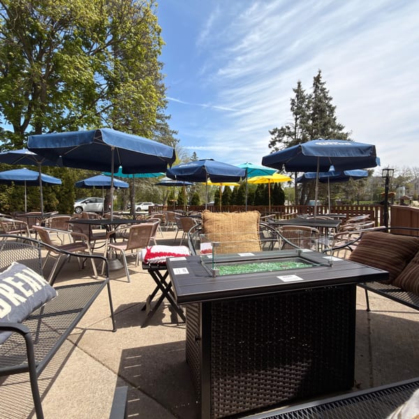 Outdoor patio with blue, yellow, and teal umbrellas, tables, chairs, and a fire pit.
